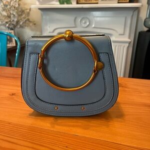 Blue bracelet bag with brass accents and crossbody strap